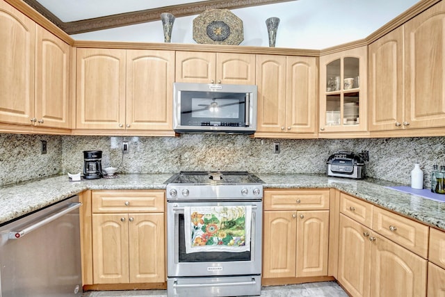 kitchen featuring stainless steel appliances, light stone counters, lofted ceiling, decorative backsplash, and light brown cabinetry