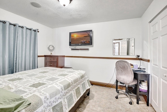 bedroom featuring a closet, light tile patterned floors, and a textured ceiling