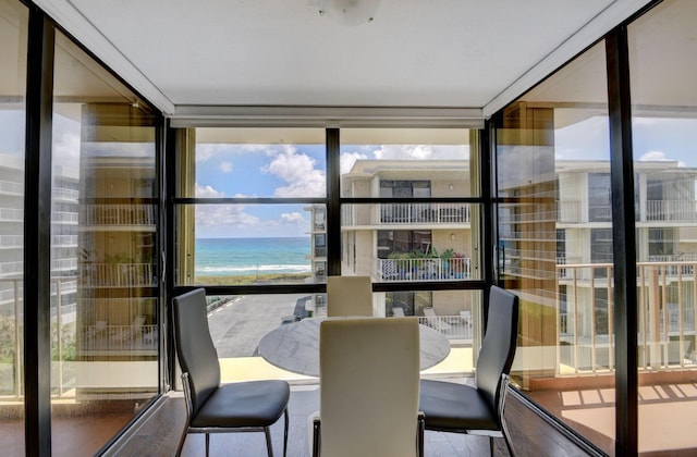 sunroom / solarium featuring a beach view and a water view