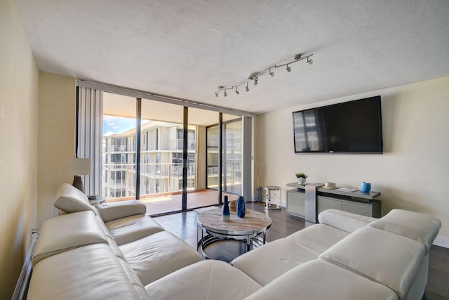 living room featuring rail lighting, dark hardwood / wood-style flooring, a wall of windows, and a textured ceiling