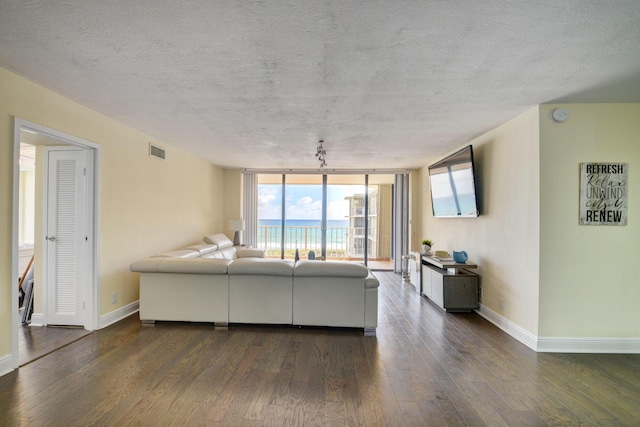 unfurnished living room featuring a textured ceiling, dark hardwood / wood-style floors, and a wall of windows