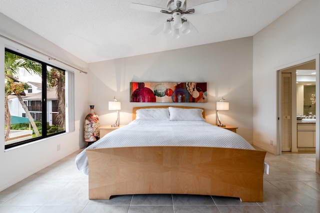 tiled bedroom with lofted ceiling, connected bathroom, and ceiling fan