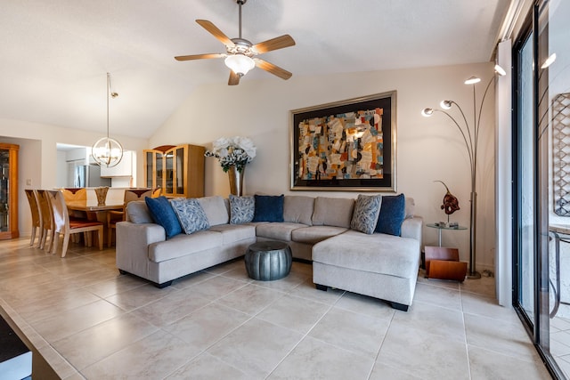 tiled living room featuring ceiling fan with notable chandelier and vaulted ceiling