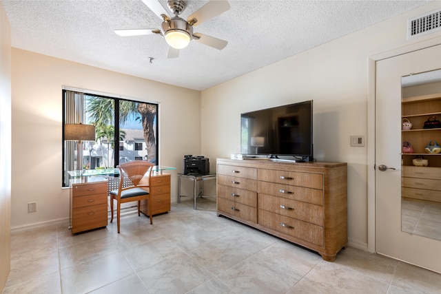 living area with ceiling fan, a textured ceiling, and light tile patterned flooring