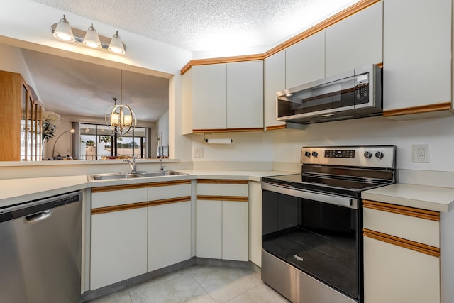 kitchen featuring sink, white cabinetry, stainless steel appliances, a textured ceiling, and decorative light fixtures