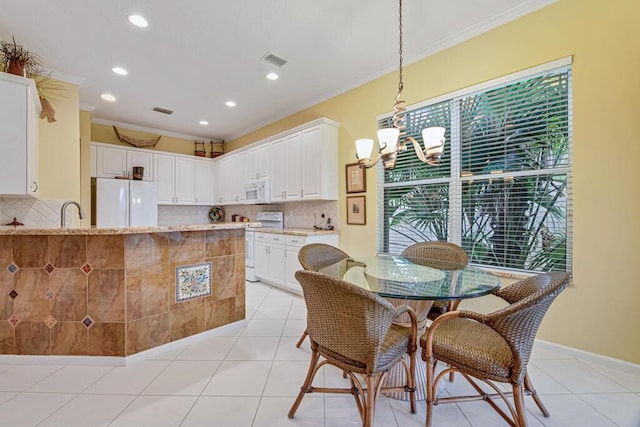 kitchen featuring white appliances, hanging light fixtures, ornamental molding, white cabinets, and light stone counters