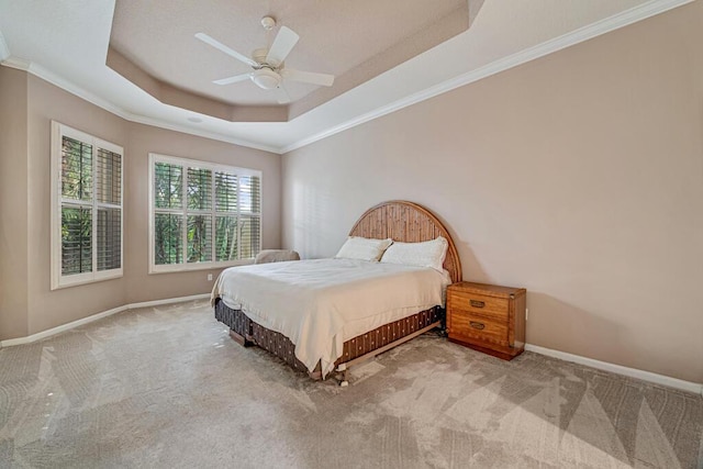 bedroom with a raised ceiling, ceiling fan, carpet, and crown molding