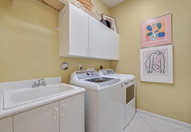 clothes washing area featuring sink, light tile patterned flooring, washer and dryer, and cabinets