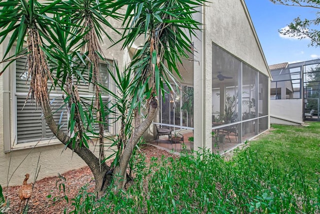 view of side of property featuring ceiling fan, a patio area, and a yard