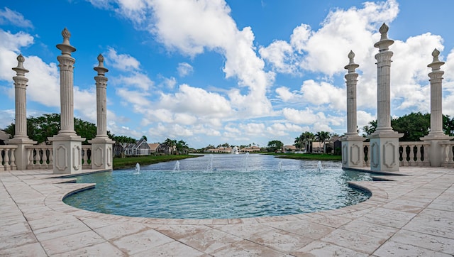 view of pool featuring a patio area, a water view, and pool water feature