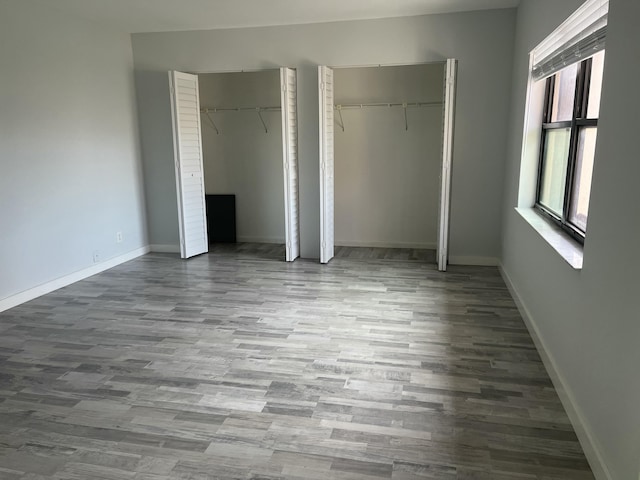 unfurnished bedroom with wood-type flooring and two closets