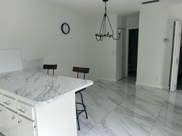 kitchen with a kitchen breakfast bar, white cabinetry, hanging light fixtures, and a notable chandelier