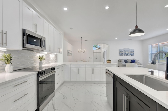 kitchen with white cabinets, appliances with stainless steel finishes, hanging light fixtures, and sink