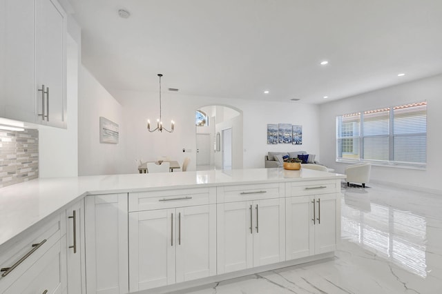 kitchen featuring kitchen peninsula, white cabinets, and decorative light fixtures