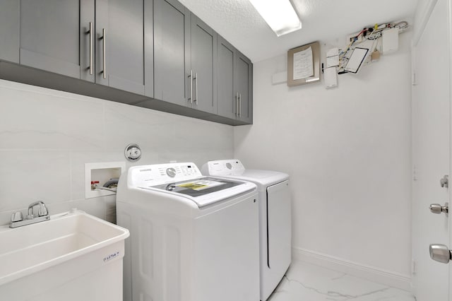 laundry area with a textured ceiling, cabinets, sink, and washing machine and clothes dryer