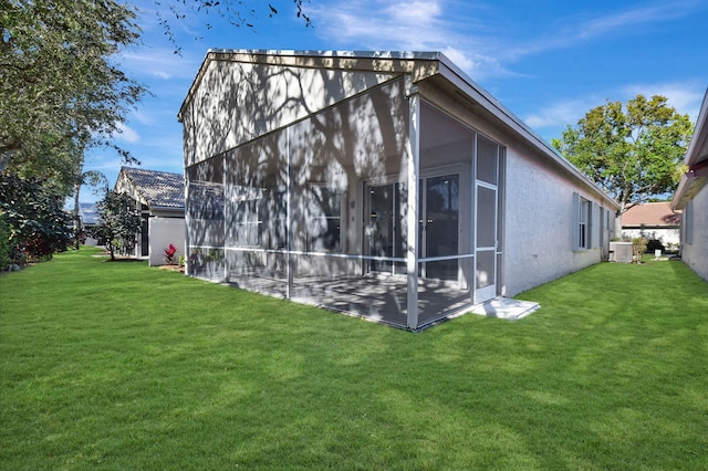 view of home's exterior with a sunroom, central AC, and a lawn