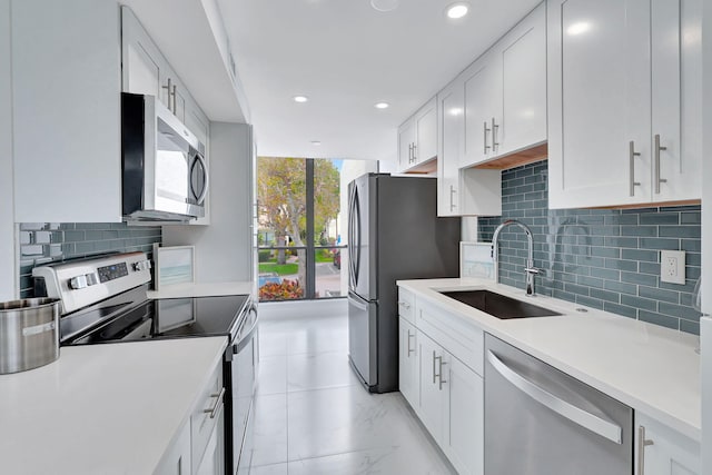 kitchen featuring decorative backsplash, appliances with stainless steel finishes, white cabinetry, and sink