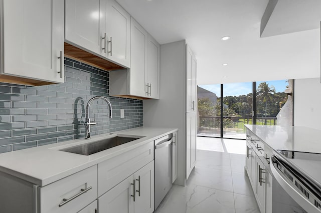 kitchen with stainless steel dishwasher, backsplash, white cabinetry, and sink