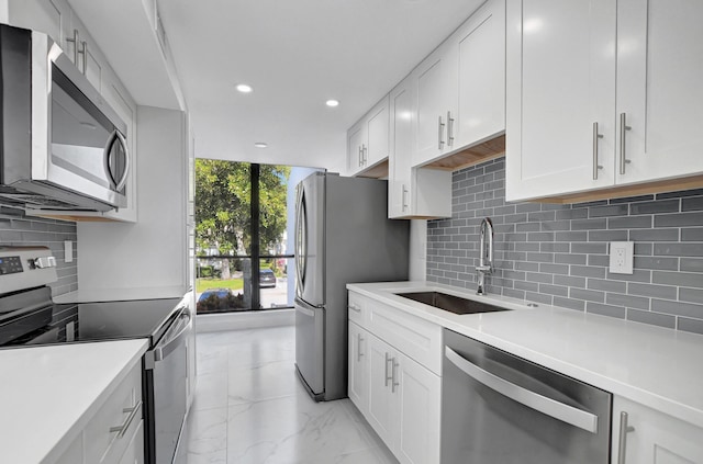 kitchen with decorative backsplash, appliances with stainless steel finishes, white cabinetry, and sink