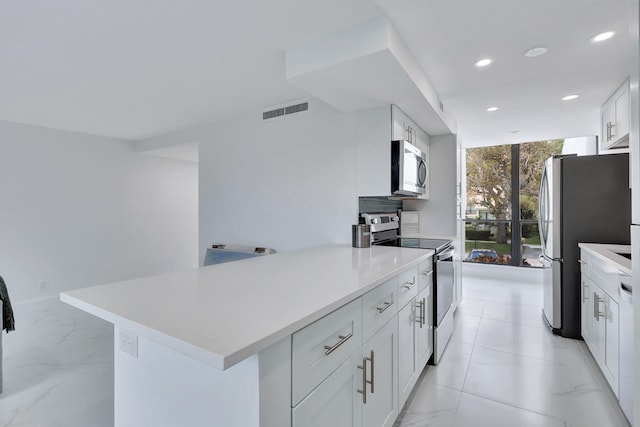 kitchen featuring decorative backsplash, white cabinetry, stainless steel appliances, and kitchen peninsula