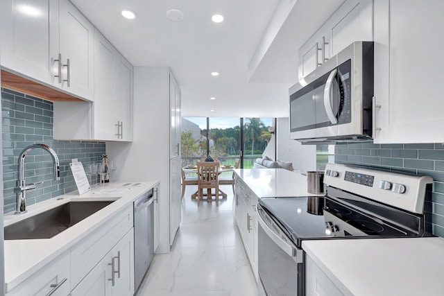 kitchen featuring backsplash, sink, white cabinets, and stainless steel appliances