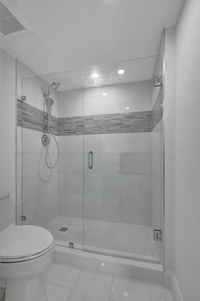 bathroom with tile patterned floors, a shower with door, and toilet