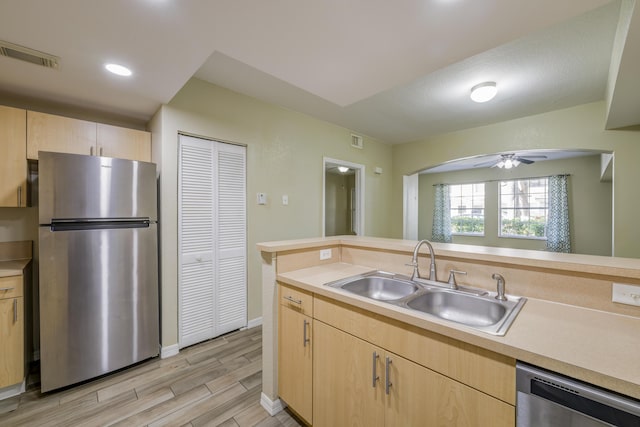 kitchen featuring appliances with stainless steel finishes, light brown cabinetry, and sink