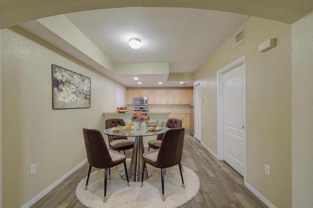 dining space with a textured ceiling and light wood-type flooring