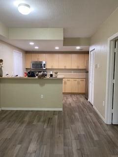 kitchen featuring kitchen peninsula, dark hardwood / wood-style flooring, and light brown cabinetry