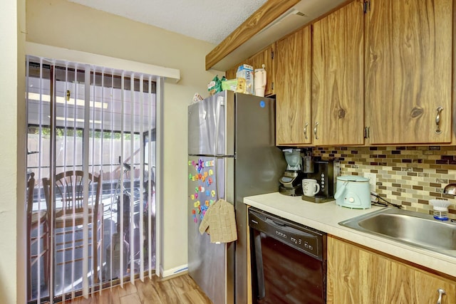 kitchen featuring dishwasher, sink, backsplash, stainless steel fridge, and light hardwood / wood-style floors