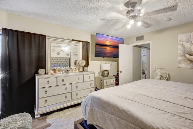 bedroom with ceiling fan, wood-type flooring, and a textured ceiling