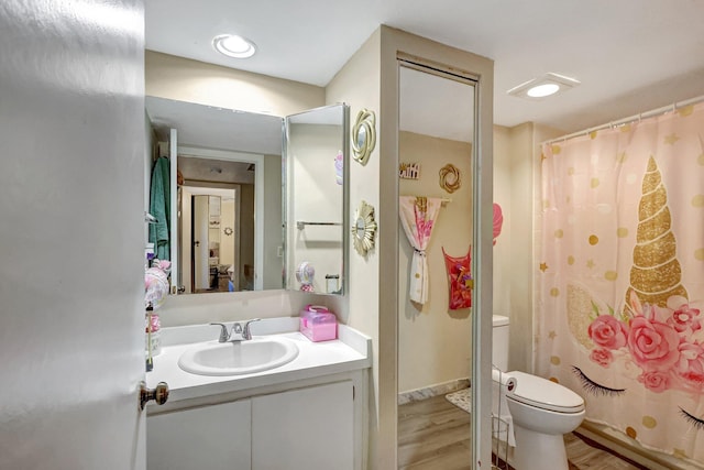 bathroom with hardwood / wood-style floors, vanity, curtained shower, and toilet