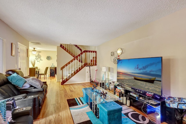 living room featuring ceiling fan, hardwood / wood-style floors, and a textured ceiling