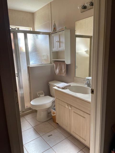 bathroom with toilet, vanity, tile patterned floors, and an enclosed shower