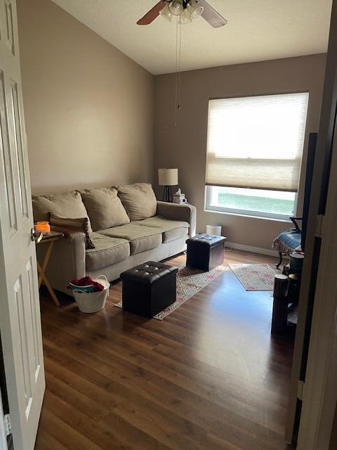 living room with ceiling fan, dark wood-type flooring, and vaulted ceiling