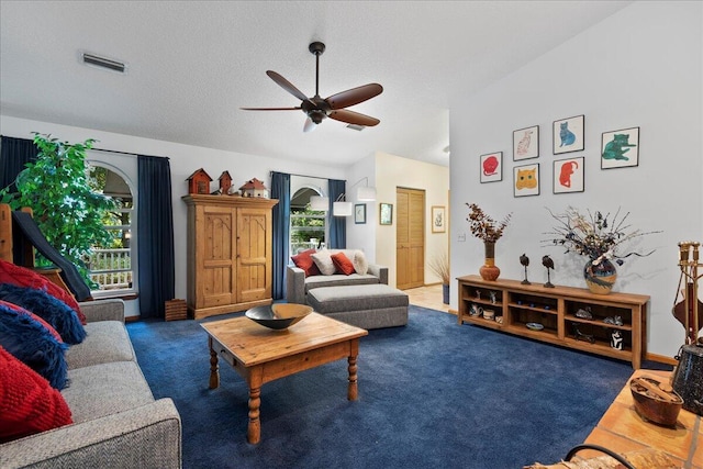 carpeted living room featuring ceiling fan and a textured ceiling