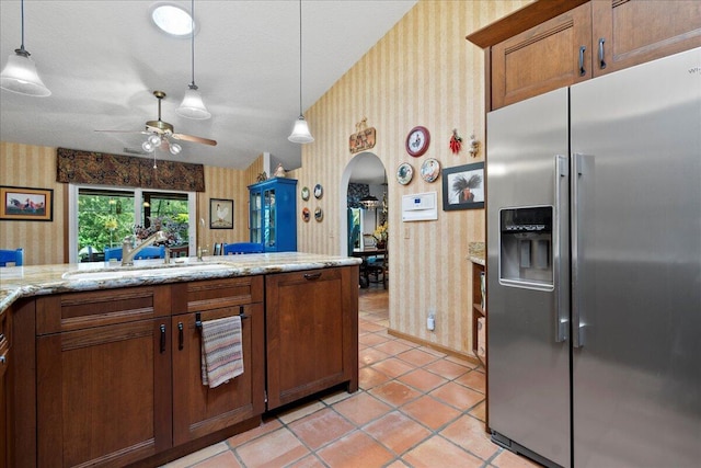 kitchen with sink, ceiling fan, a textured ceiling, light stone counters, and stainless steel fridge with ice dispenser