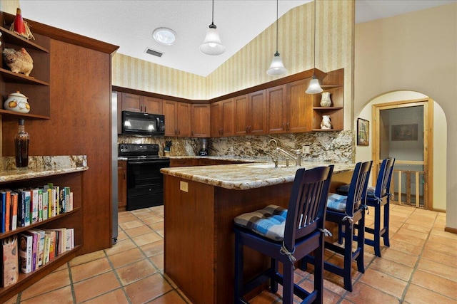 kitchen with kitchen peninsula, decorative light fixtures, decorative backsplash, a breakfast bar, and black appliances