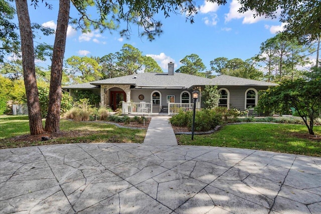 view of front facade with a front yard, a chimney, and a porch