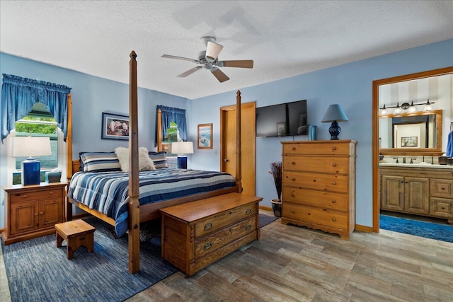 bedroom with ensuite bathroom, hardwood / wood-style floors, ceiling fan, and a textured ceiling