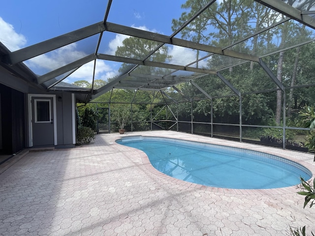 outdoor pool with a patio and glass enclosure