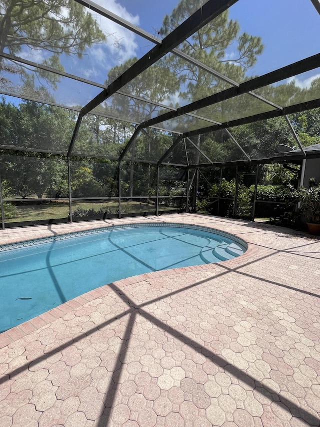 outdoor pool featuring a patio area and glass enclosure