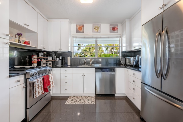 kitchen featuring stainless steel appliances, dark countertops, and white cabinetry