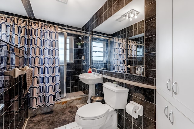 bathroom featuring a stall shower, tile walls, toilet, and tile patterned floors