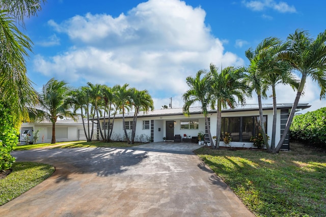 single story home featuring concrete driveway, metal roof, and a front lawn