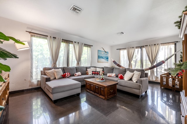 living room featuring plenty of natural light, visible vents, and granite finish floor