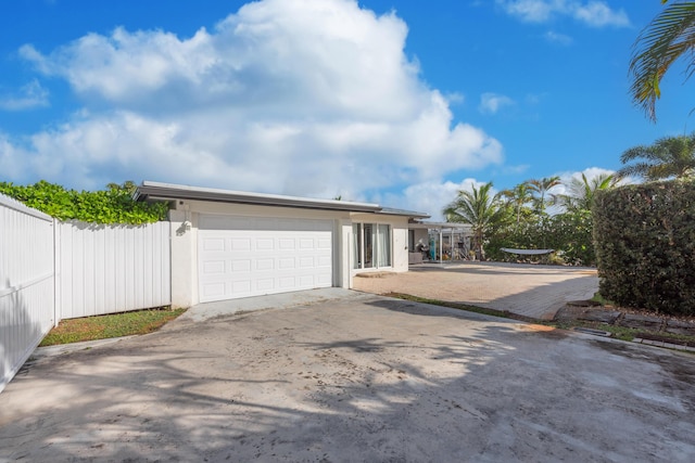 view of front facade featuring a garage, concrete driveway, fence, and stucco siding