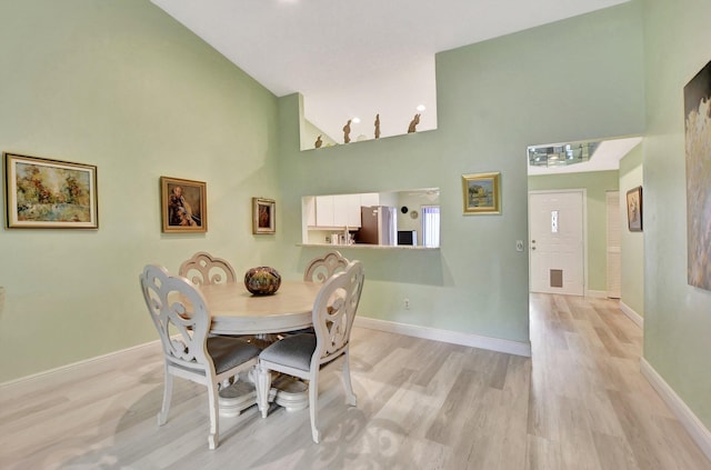 dining space featuring high vaulted ceiling and light hardwood / wood-style flooring