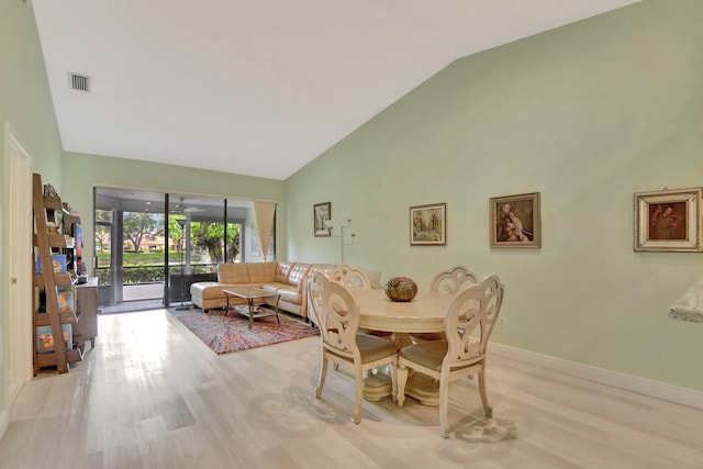 dining room featuring high vaulted ceiling and light wood-type flooring