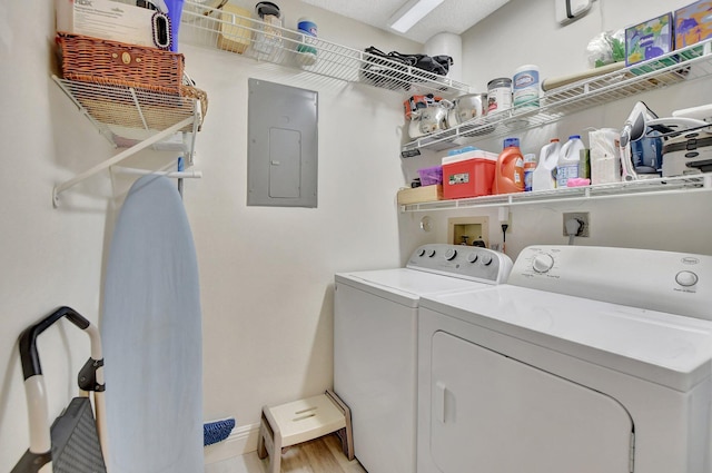 laundry area with light hardwood / wood-style floors, separate washer and dryer, and electric panel